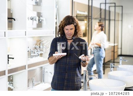 Man looking to buy new faucet for bathroom sink in store Man looking to buy new faucet for bathroom sink in store 107264285