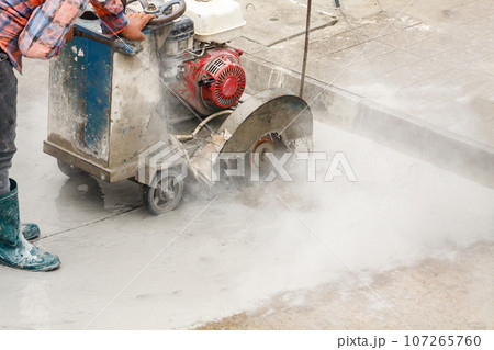 Worker using diamond saw blade machine cutting concrete road at construction site Worker using diamond saw blade machine cutting concrete road at construction site 107265760