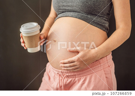 Pregnant woman with a paper cup of coffee. The benefits or harms of coffee for pregnant women Pregnant woman with a paper cup of coffee. The benefits or harms of coffee for pregnant women 107266859