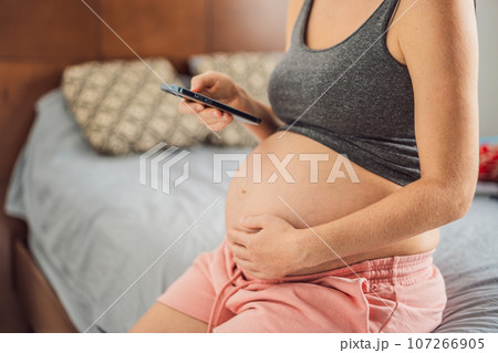 Mobile pregnancy online maternity application. Pregnant mother using phone. Pregnancy, medicine, pharmaceutics, health care and people concept 107266905