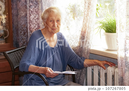 Woman holding cash in front of heating radiator. Payment for heating in winter. Selective focus. Woman holding cash in front of heating radiator. Payment for heating in winter. Selective focus. 107267805
