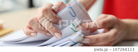 Woman looks for necessary materials sitting at wooden table Woman looks for necessary materials sitting at wooden table 107268113