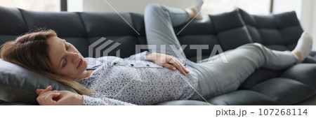 Tired woman relaxes on comfortable sofa after hard work Tired woman relaxes on comfortable sofa after hard work 107268114