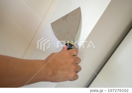 Man repairing crack white wall with spatula 107270102