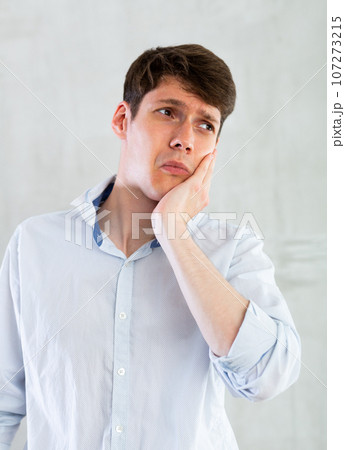 Unhappy man having a toothache in living room Unhappy man having a toothache in living room 107273215