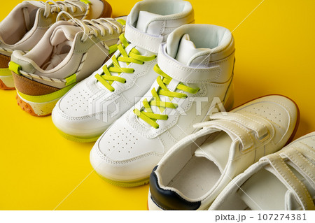 Several pairs of fashion trendy sport shoes on yellow background Several pairs of fashion trendy sport shoes on yellow background 107274381
