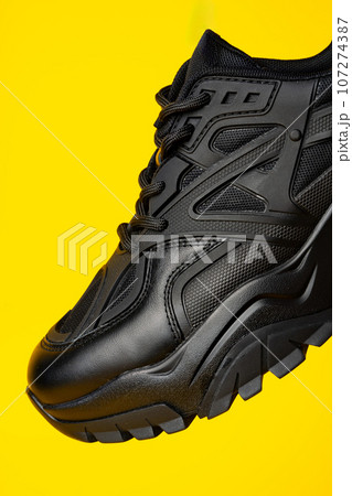 Black new sport sneakers on yellow background Black new sport sneakers on yellow background 107274387