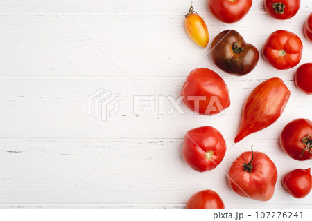 Fresh harvest of red tomatoes on a white wooden table. Top view. 107276241