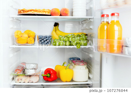 Open fridge or refrigerator door filled with fresh fruits, vegetables, juice 107276844