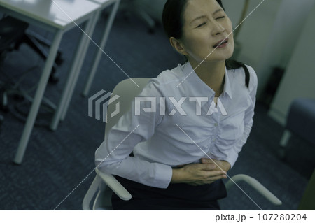 オフィスでお腹を押さえて苦しむミドルエイジの女性 107280204