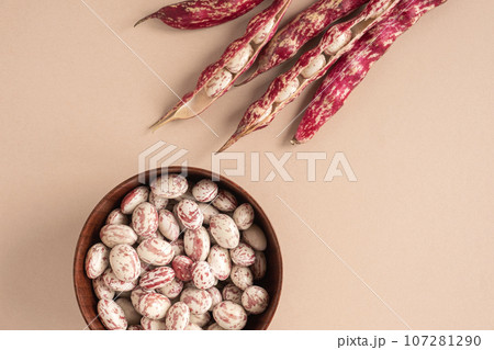 Cranberry beans. Borlotti bean pods in bowl. Top view. Stylish modern food background. Magenta color. Creative foodstuff flat lay. Grocery, dietary backdrop. Advertising, trendy magazine publication. Cranberry beans. Borlotti bean pods in bowl. Top view. Stylish modern food background. Magenta color. Creative foodstuff flat lay. Grocery, dietary backdrop. Advertising, trendy magazine publication. 107281290