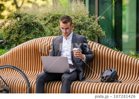 Handsome young businessman working on laptop and drinking coffee 107281426
