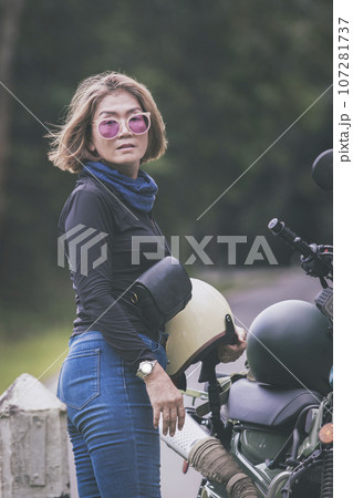 pretty woman holding safety helmet standing beside small enduro motorcycle pretty woman holding safety helmet standing beside small enduro motorcycle 107281737
