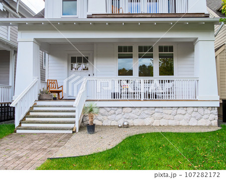 Entrance of detached residential house with rocking chair on front patio 107282172