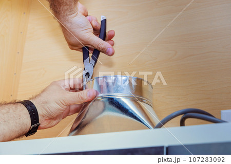 Worker installation placing tube for kitchen hood on kitchen 107283092