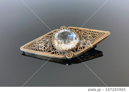 Vintage silver filigree brooch with rhinestone made in 1954 in USSR on dark glossy background 107283985