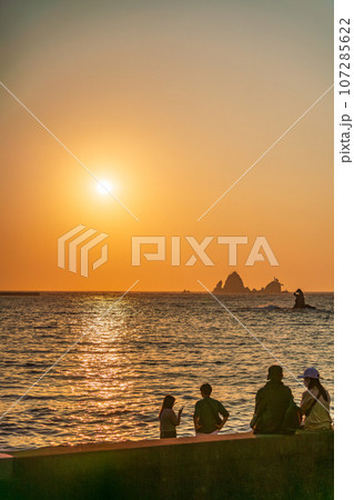 （静岡県）西伊豆・大田子海岸の夕陽を眺めるカップル 107285622
