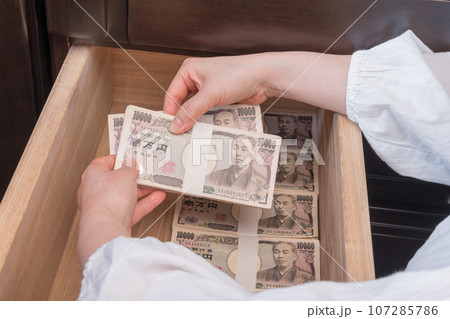 【たんすの引き出しに札束を隠す主婦】 107285786