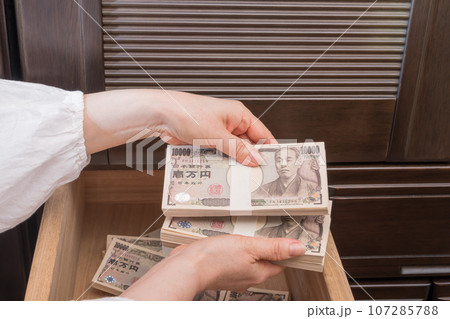 【たんすの引き出しに札束を隠す主婦】 107285788