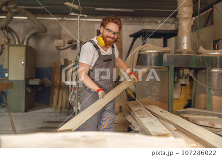 Professional male carpenter working on carpentry manufacturing with wooden board 107286022