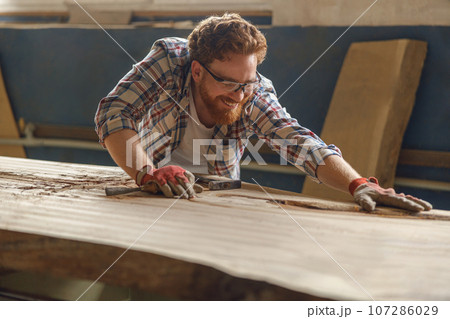 Professional craftsman working with chisel while cutting wooden plank in carpentry workshop Professional craftsman working with chisel while cutting wooden plank in carpentry workshop 107286029