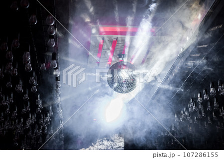 Disco bright shiny ball on the ceiling in smoke in the interior of a nightclub 107286155