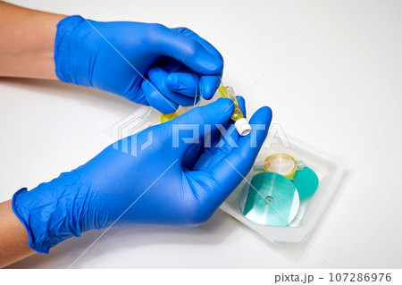 Preparation for epidural anesthesia. Epidural anesthesia kit and medical professional's hands in protective gloves close-up Preparation for epidural anesthesia. Epidural anesthesia kit and medical professional's hands in protective gloves close-up 107286976