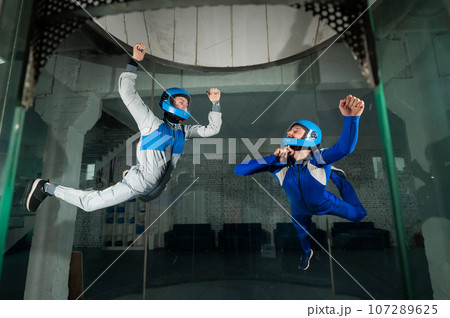 A man and a woman enjoy flying together in a wind tunnel. Free fall simulator A man and a woman enjoy flying together in a wind tunnel. Free fall simulator 107289625