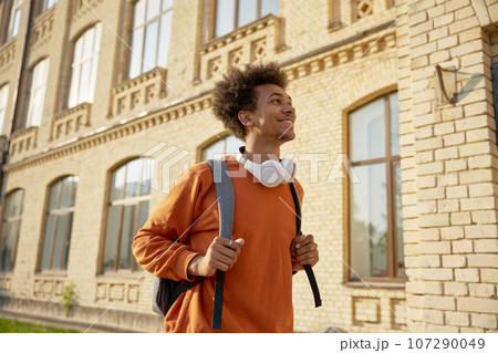 Exited teenage student walking among buildings of university campus 107290049