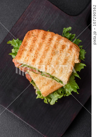 Delicious crispy sandwich with toast, salmon, avocado, tomatoes, salt, spices and herbs 107290562