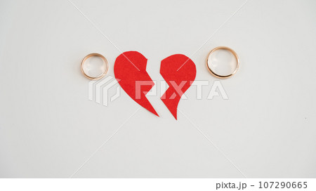 Broken heart and wedding rings on a white background. Divorce concept. Broken heart and wedding rings on a white background. Divorce concept. 107290665