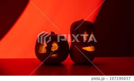 Two jack-o-lanterns glow in the dark on a red background. Halloween decoration. 107290837