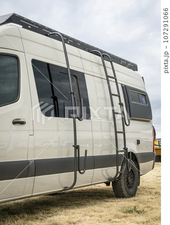 Camper van with a roof ladder and surfboard or paddleboard racks. 107291066