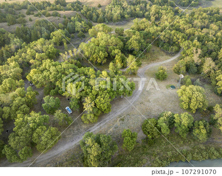 Whitetail Campground on the shore of Dismal River in Nebraska National Forest, late summer dawn aerial view with SUV vehicle 107291070