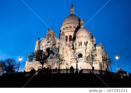 The Basilica of Sacre Coeur de Montmartre illuminated in the evening. Roman Catholic church and minor basilica in Paris dedicated to the Sacred Heart of Jesus. France The Basilica of Sacre Coeur de Montmartre illuminated in the evening. Roman Catholic church and minor basilica in Paris dedicated to the Sacred Heart of Jesus. France 107291211