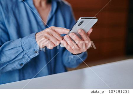 部屋でスマホを操作するシニア女性 107291252