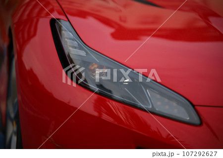 Close-up of the headlight of a red sports car. 107292627