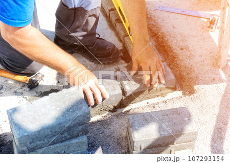 Mason lays out brickwork from gray bricks. Hands of builder with trowel close-up. Man works at 107293154