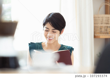 リビングで手帳を見る女性 107293374