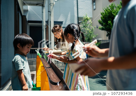 お庭で雨どい流しそうめんをする家族 お庭で雨どい流しそうめんをする家族 107293436