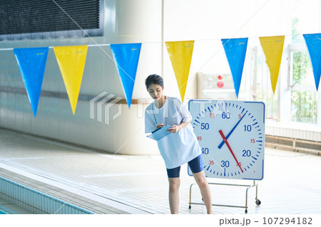 プールサイドでタイムをチェックするコーチ プールサイドでタイムをチェックするコーチ 107294182