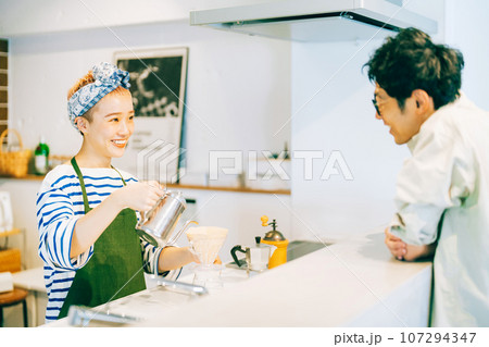 キッチンでコーヒーを淹れる女性と見守る男性 キッチンでコーヒーを淹れる女性と見守る男性 107294347