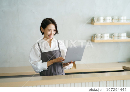 ノートパソコンを持つカフェ店員 107294443