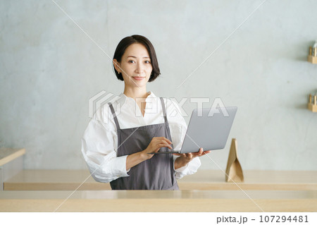 ノートパソコンを持つカフェ店員 107294481
