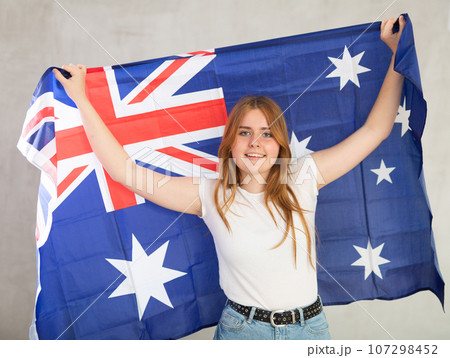 smiling girl in arms raised above head holds canvas of national flag of Australia smiling girl in arms raised above head holds canvas of national flag of Australia 107298452