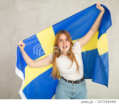 smiling girl in arms raised above head holds cloth of national flag of Sweden smiling girl in arms raised above head holds cloth of national flag of Sweden 107298469