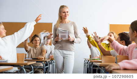 Pupils raising hands during lesson in school 107298605