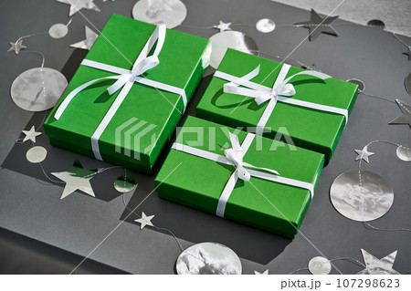 Green boxes with gifts on a gray. 107298623