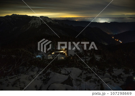 11月の曇天の下、北アルプスの稜線から山小屋の灯りと岐阜県高山市の夜景 11月の曇天の下、北アルプスの稜線から山小屋の灯りと岐阜県高山市の夜景 107298669
