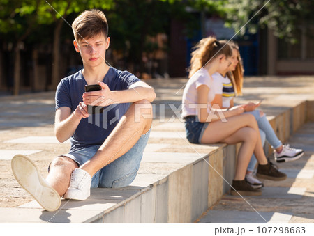 Teenager is passionate about playing on a smartphone on street 107298683